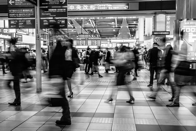 Bahnhof voller Menschen, die durch das Bild eilen.